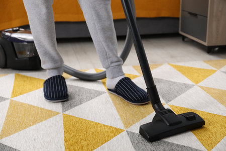 Man with vacuum cleaning carpet indoors, closeupの写真素材