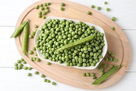Fresh green peas and pods on white wooden table, flat layの写真素材