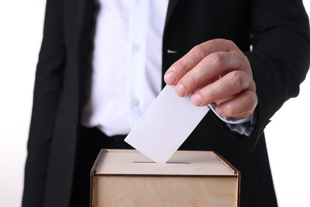 Man putting his vote into ballot box against white background, closeupの写真素材