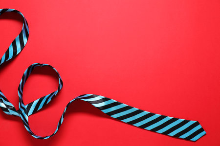 Striped necktie on red background, top view. Space for textの写真素材