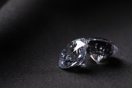 Two beautiful shiny diamonds on black fabric, closeup. Space for textの写真素材