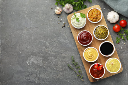 Many different sauces and products on gray table, flat lay. Space for textの写真素材