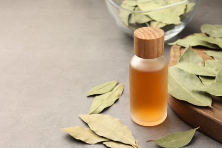 Bottle of bay essential oil and dried leaves on light gray table. Space for textの写真素材