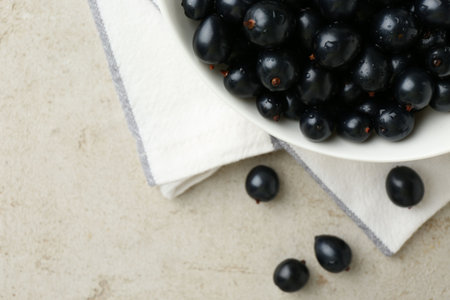 Ripe black currents in bowl on light table, top view. Space for textの写真素材