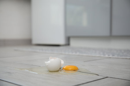 Broken raw egg and shell on light grey wooden floor indoorsの写真素材