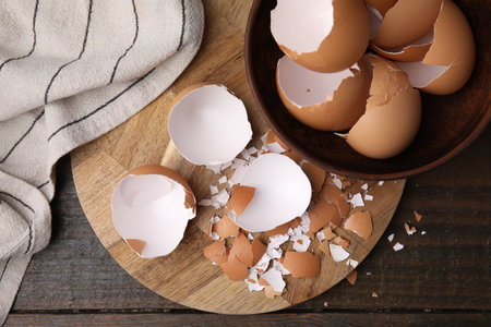 Pieces of broken eggshells on wooden table, top view