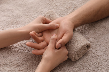 Man receiving hand massage on soft towel, closeupの写真素材