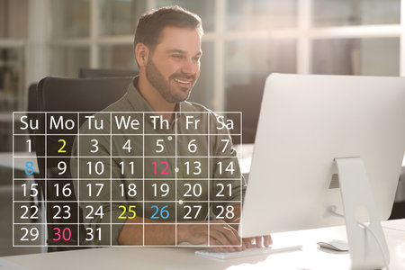 Happy man making timetable in computer. Virtual calendar with marked dates in foregroundの写真素材