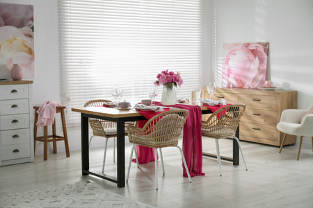 Pink peonies on table with beautiful setting and rattan chairs in dining roomの写真素材