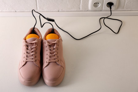 Shoes with electric dryer on floor indoors, space for textの写真素材