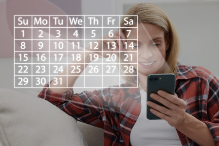 Making timetable. Woman using smartphone. Virtual calendar projected from deviceの写真素材