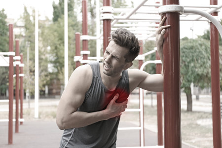 Heart attack. Man suffering from pain in chest at outdoor gymの写真素材