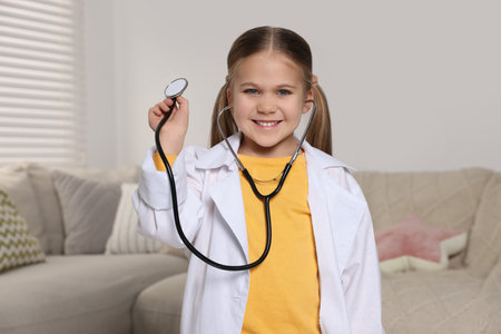 Little girl in medical uniform with stethoscope at homeの写真素材