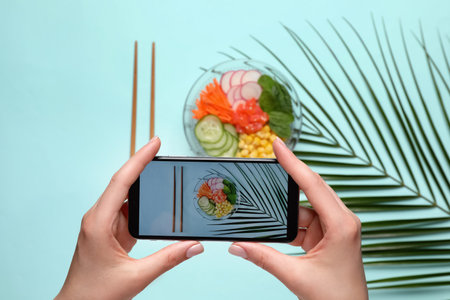 Blogger taking photo of lunch on turquoise background, top view