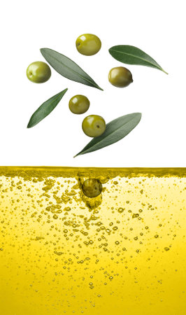 Green olives and leaves falling into cooking oil on white backgroundの写真素材