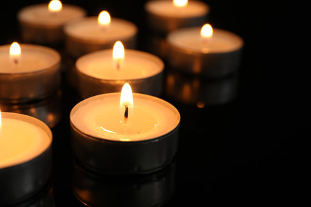 Many burning tealight candles on black background, closeupの写真素材