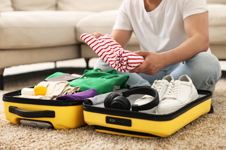 Man packing suitcase on floor at home, closeupの写真素材