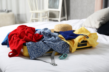 Open suitcase with traveler's belongings on bedの写真素材