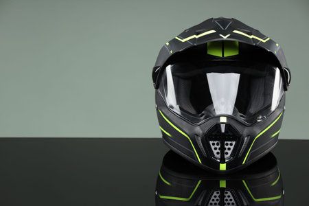 Modern motorcycle helmet with visor on mirror surface against light gray background. Space for text
