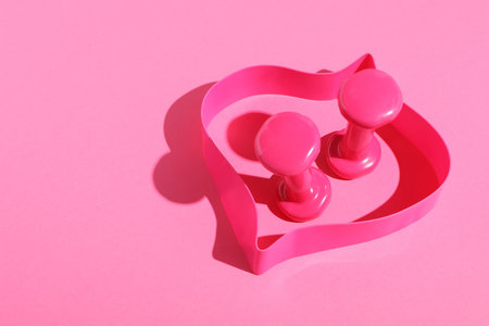 Dumbbells and fitness elastic band on pink background. Space for textの写真素材