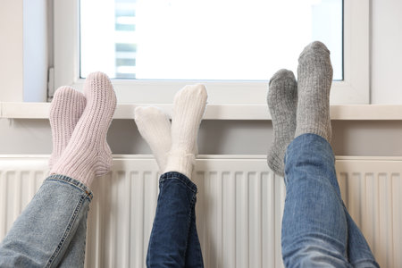 Family warming feet near heating radiator at home, closeupの写真素材