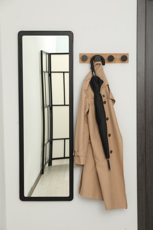 Black umbrella, coat, rack and mirror in hallwayの写真素材