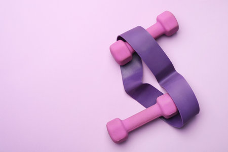 Two dumbbells and fitness elastic band on violet background, top view. Space for textの写真素材
