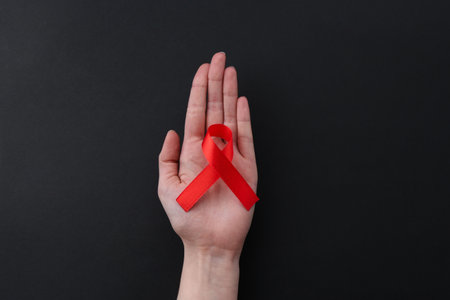 Woman with red awareness ribbon on black background, top viewの写真素材