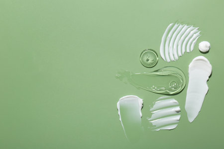Samples of face cream on green background, top view. Space for textの写真素材
