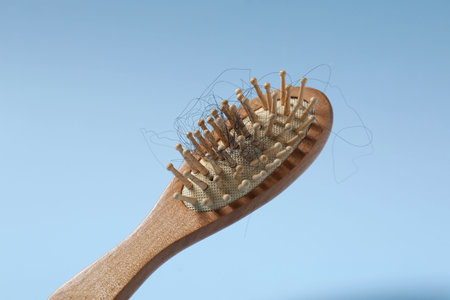 Wooden brush with lost hair in air on light blue backgroundの写真素材