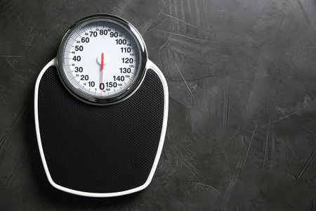 One bathroom scale on gray textured background, top view. Space for text