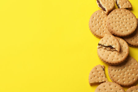 Tasty sandwich cookies on yellow background, top view. Space for textの写真素材