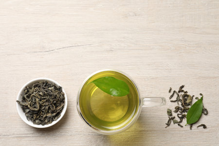Refreshing green tea in cup and leaves on wooden table, flat lay. Space for textの写真素材