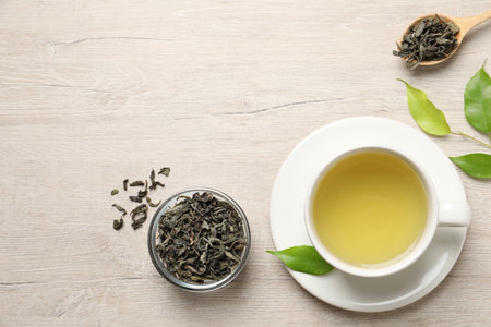 Refreshing green tea in cup, spoon and leaves on wooden table, flat lay. Space for textの写真素材