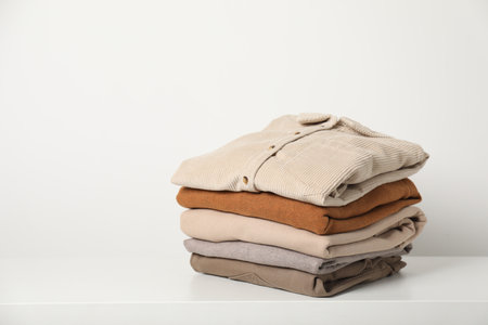 Stack of clothes on white shelf indoors, space for textの写真素材