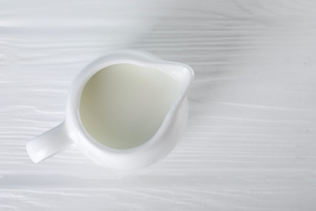 Jug of fresh milk on white wooden table, top view. Space for textの写真素材