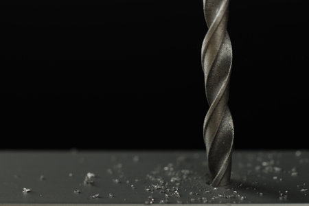 Drilling hole in gray surface on black background, closeup. Space for text