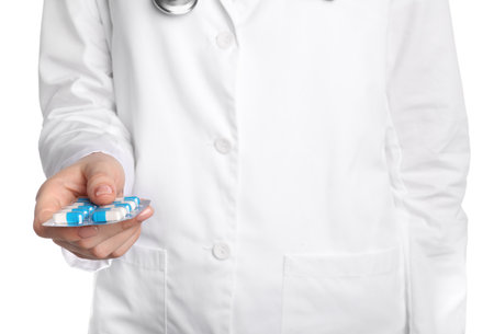 Doctor holding blister with antibiotic pills on white background, closeupの写真素材