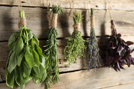 Bunches of different aromatic herbs hanging on rope near wooden wall, closeupの写真素材