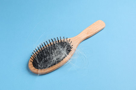 Wooden brush with lost hair on light blue backgroundの写真素材