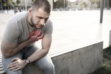 Heart attack. Young man suffering from pain in chest outdoors