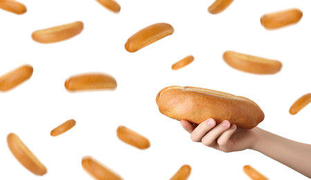 Woman holding hot dog bun against flying ones on white backgroundの写真素材