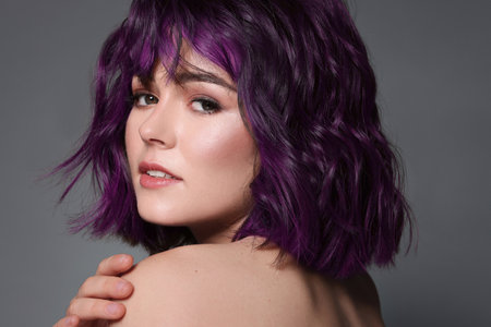 Beautiful young woman with purple hair on grey backgroundの写真素材