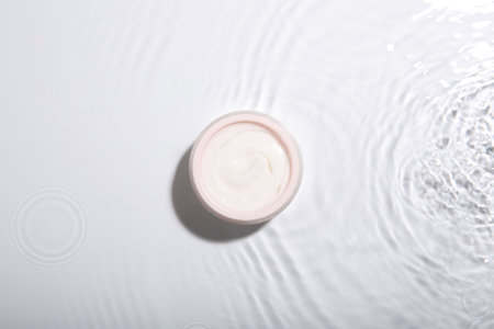Cosmetic product. Jar with cream in water on light background, top viewの写真素材