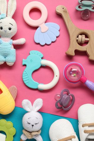Different baby rattles and boots on color background, flat lay