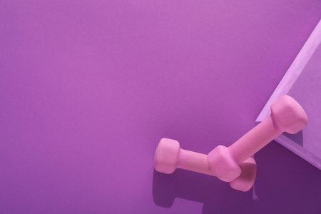 Dumbbells and yoga block on purple background, flat lay. Space for textの写真素材