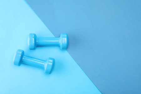 Two dumbbells on blue background, top view. Space for textの写真素材