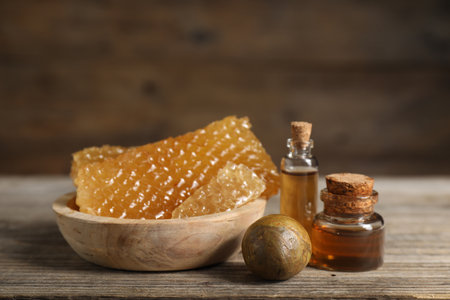 Natural honey tincture and sweet honeycombs on wooden table, closeupの写真素材