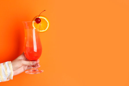 Woman with glass of refreshing cocktail on orange background, closeup. Space for textの写真素材