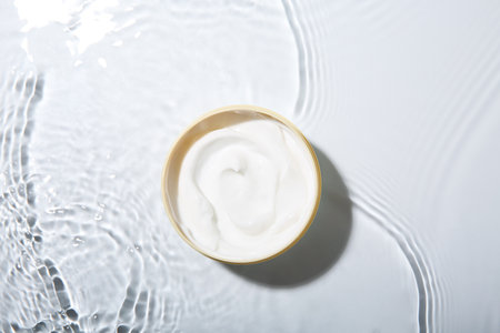 Cosmetic product. Jar with cream in water on light background, top viewの写真素材